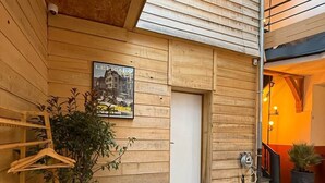 Fachada de madera con una puerta, una planta colgante y un cartel en la pared.