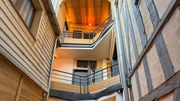 Un interior de varios niveles con paneles de madera, una escalera y un área de descanso con plantas en macetas.