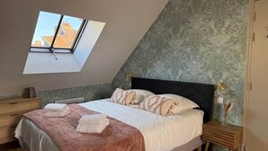 Ein Schlafzimmer mit Oberlicht, einem Bett mit Kissen, einem Nachttisch und einem Beistelltisch.