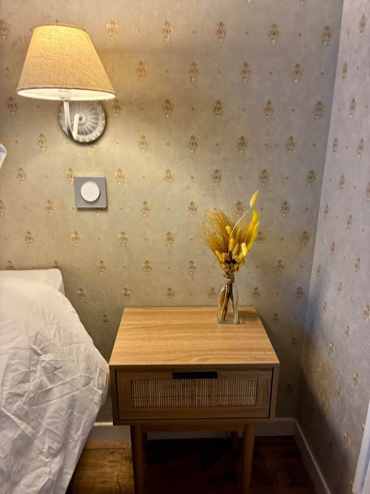 Ein Schlafzimmer mit einem Bett, einem Nachttisch mit einer Lampe und einer Wanduhr.