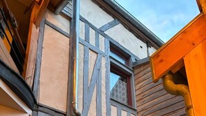 Ein traditionelles Fachwerkhäuschen mit freiliegenden Holzbalken und einem Fenster mit Vorhang.