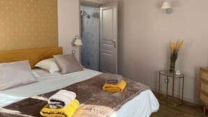 Ein Hotelzimmer mit Bett, Nachttisch, Lampe, Tür und einem kleinen Tisch mit einer Vase.