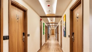 A hotel hallway with wooden doors, numbered room signs, and recessed ceiling lighting. - Lords Inn Katra (Katra)
