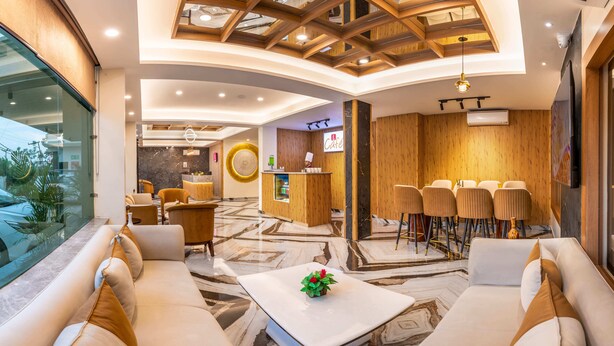 A hotel lobby with a reception desk, seating area, and a view through a glass wall. - Lords Inn Katra (Katra)