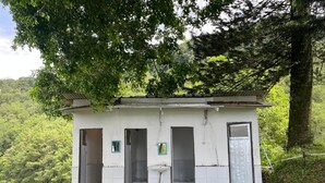 A small, single-story building with a white exterior, multiple doors, a window, and a door. - Masada Village (Cisarua)