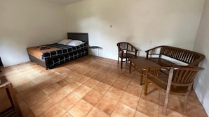 A bedroom with a bed, a small table, a chair, and a wooden bench. - Masada Village (Cisarua)