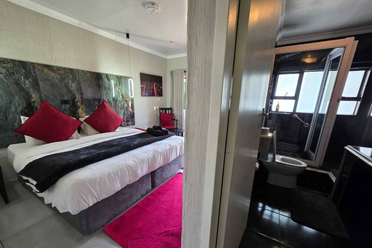 Habitación de hotel moderna con una cama grande, zona de ducha y vistas a la ciudad.