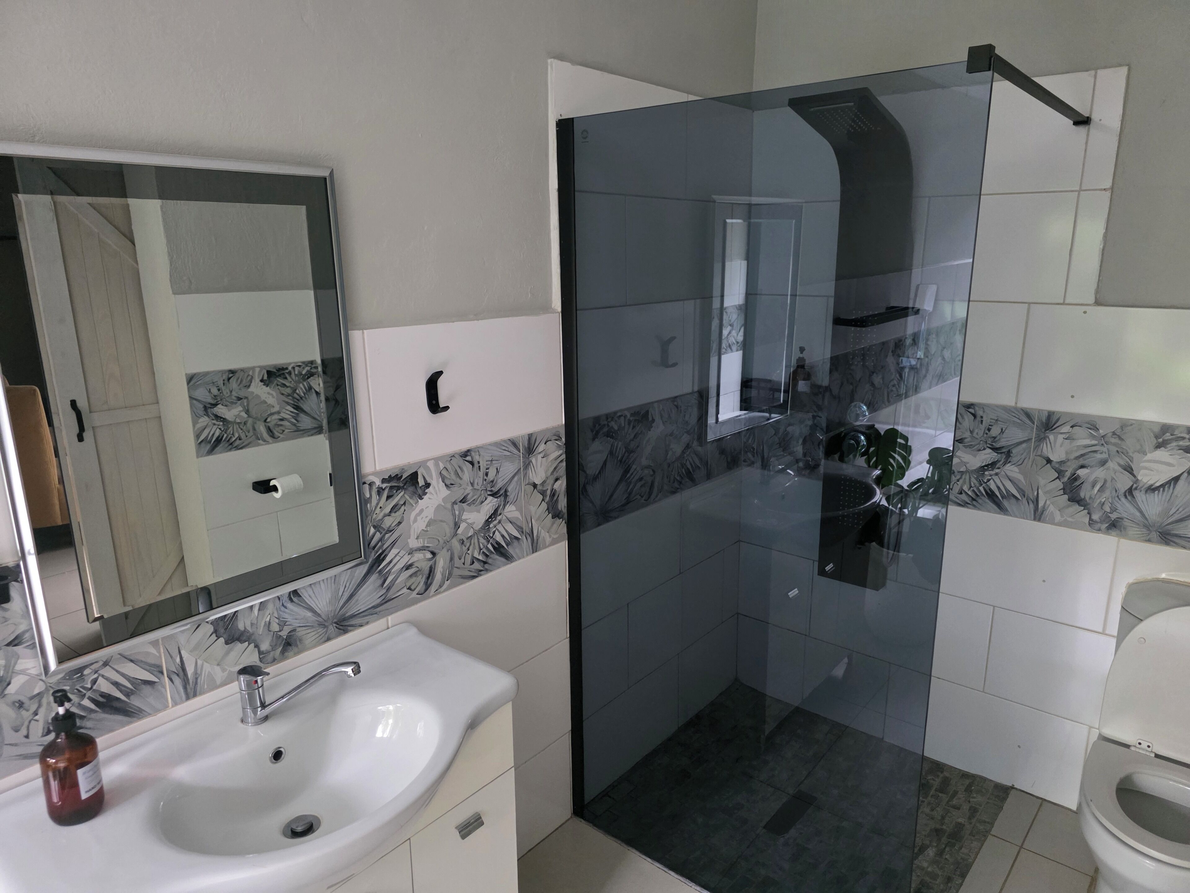 Ein Badezimmer mit Duschkabine, Waschbecken mit Spiegel und Toilette.