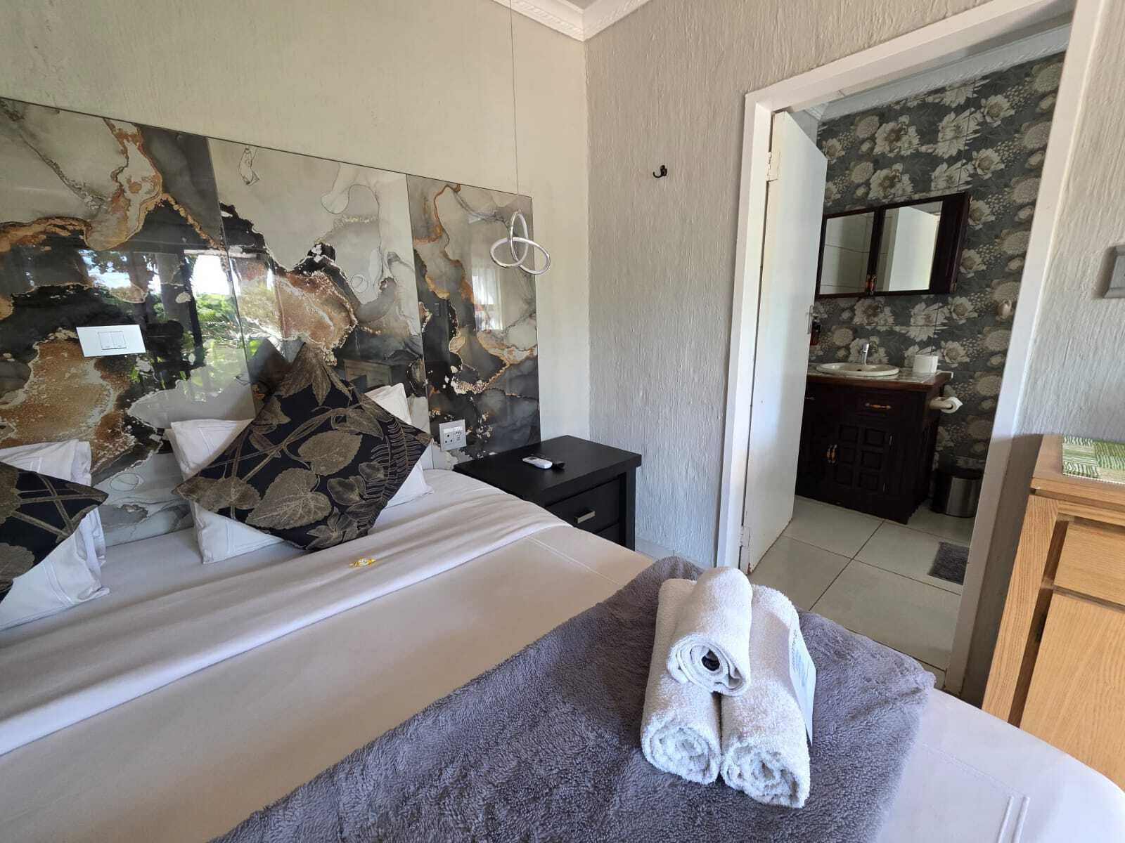 Habitació d'hotel amb llit, bany i un mirall que reflecteix l'espai.