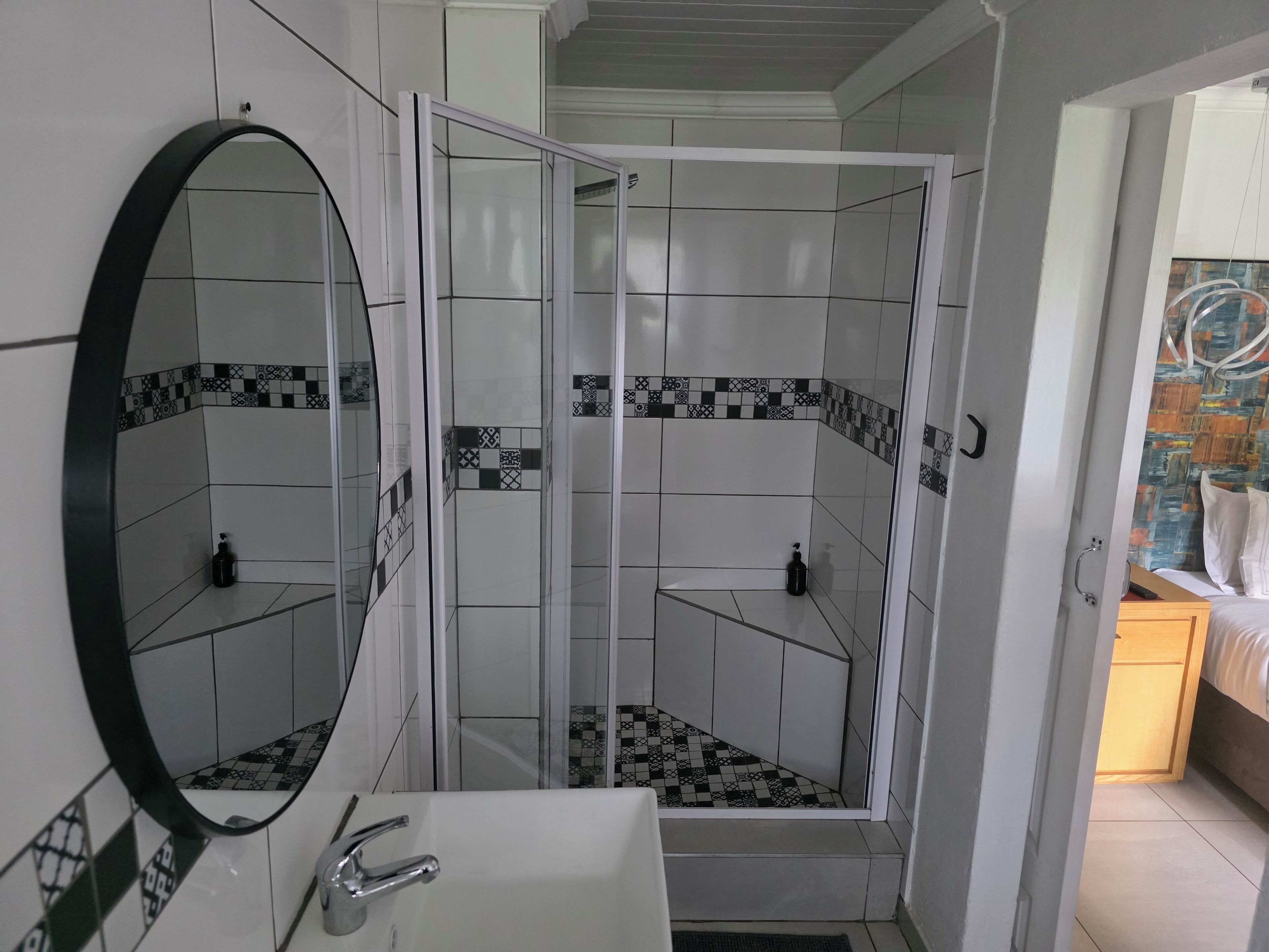 A bathroom with a shower, a sink, and a mirror.