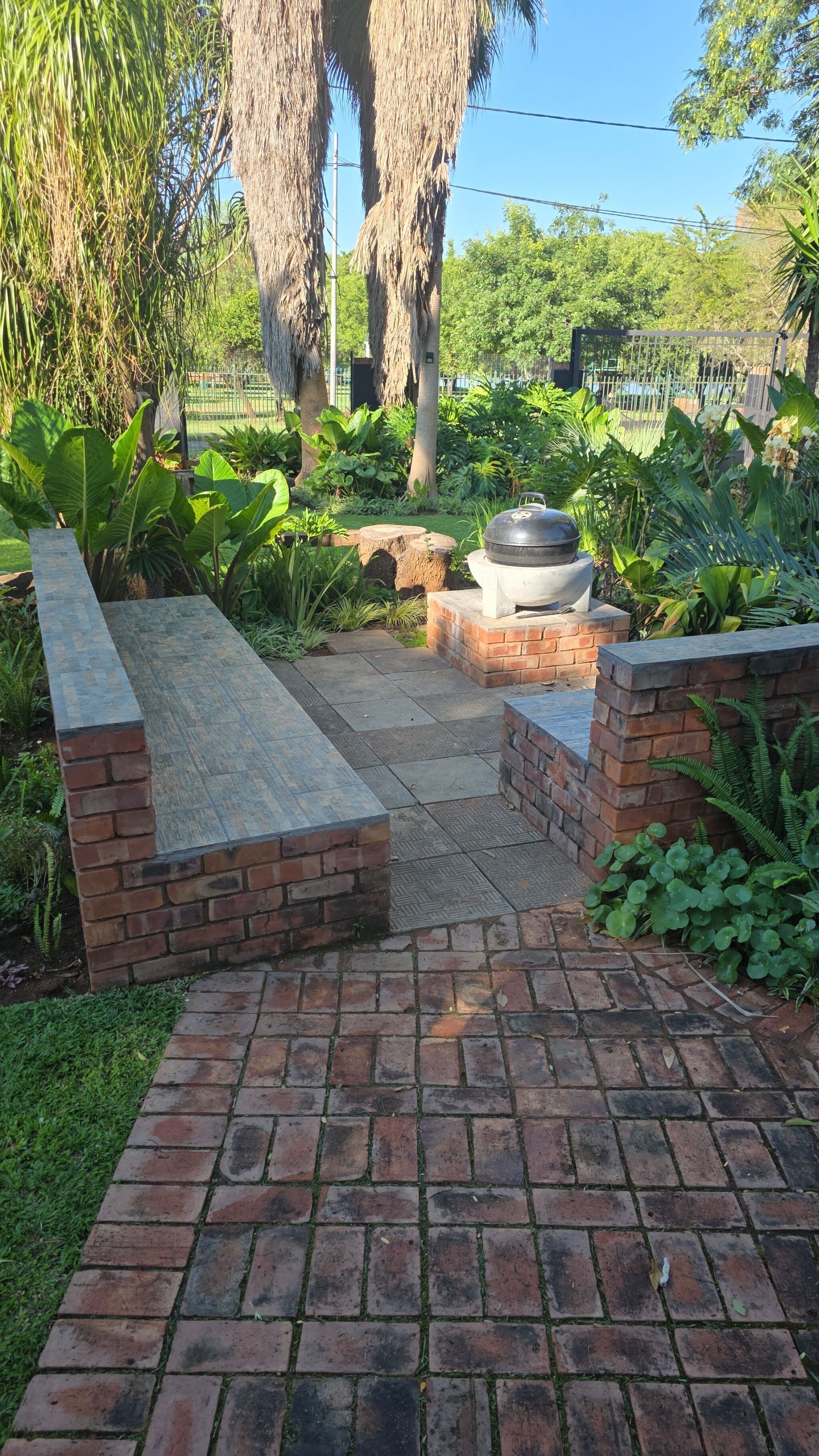 A paved patio with brick walls and a grill area.