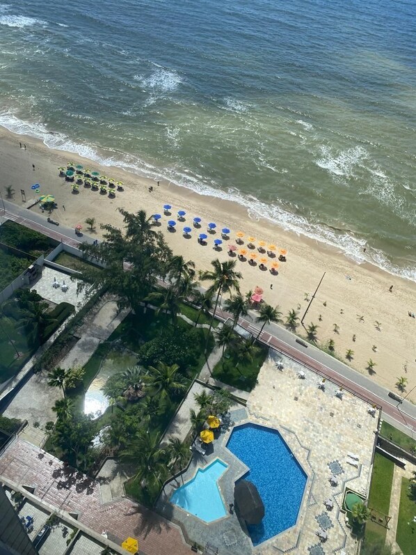 A beach with umbrellas and a swimming pool. - FLATS GOLDEN BEACH APARTMENTS (Jaboatão dos Guararapes)