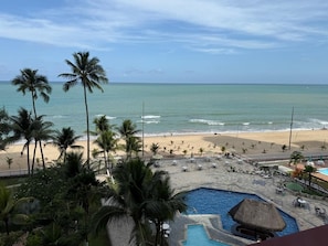 Un resort frente al mar con piscina, palmeras y vistas al océano.