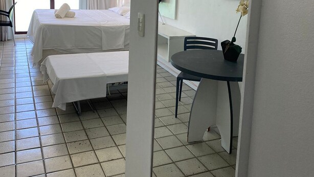 Habitación de hotel con dos camas, una mesa de comedor y un ventanal grande.
