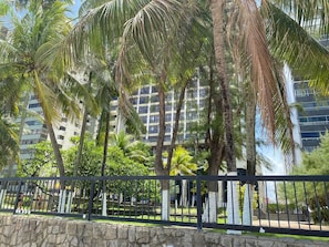 A stone wall, a black metal fence, and tall buildings in the background. - FLATS GOLDEN BEACH APARTMENTS (Jaboatão dos Guararapes)