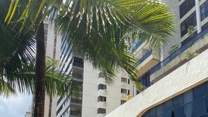 Un edificio moderno con amplios ventanales, piscina y zona de estar exterior con sombrillas.