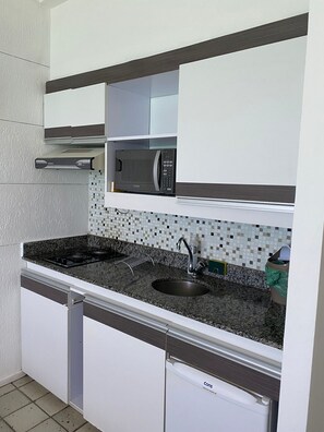 Uma cozinha com micro-ondas, pia e fogão.