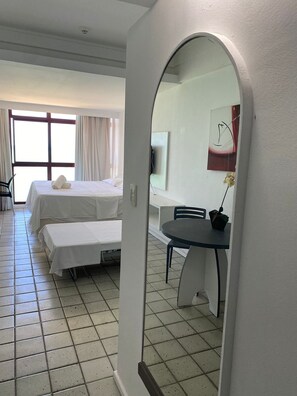 Quarto de hotel com duas camas, uma mesa de jantar e uma janela grande.
