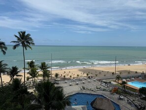 A beach resort with a swimming pool, palm trees, and a view of the ocean. - FLATS GOLDEN BEACH APARTMENTS (Jaboatão dos Guararapes)