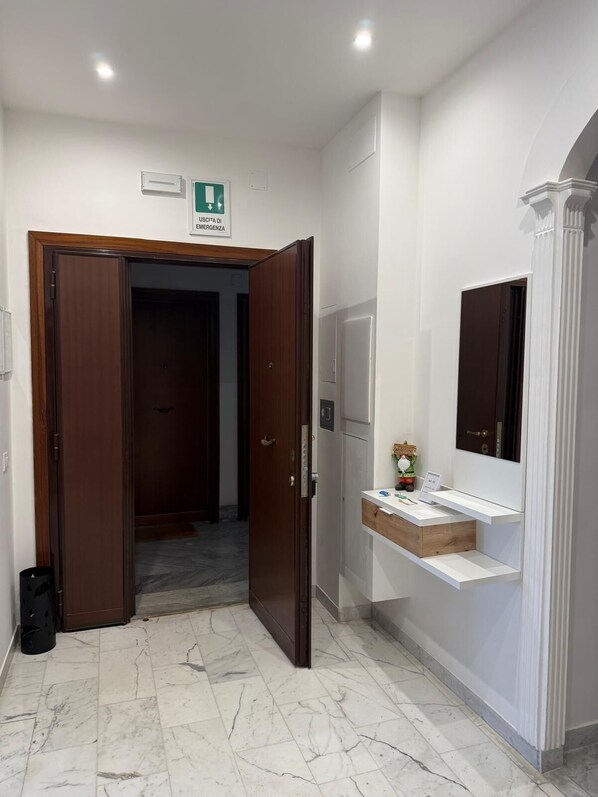 A hotel room with a marble floor, a wooden door, a white reception desk, and a mirror. - Dimora247Elegant 2BR 2BA Apartment in Roma Balduina, peaceful stay near Vaticano (Roma)