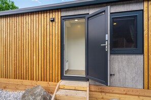 Ein modernes Gebäude mit Holzfassade, einer Schiebetür und einer kleinen Holztreppe, die zu einer Tür führt.