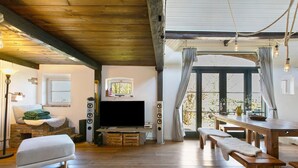 Una sala de estar con televisión, bancos de madera, chimenea y un ventanal grande.