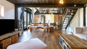 Un amplio salón con piso de madera, televisor y una escalera que lleva a un nivel superior.