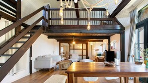 Amplio espacio tipo loft con escalera de madera, una gran mesa de comedor y una zona de estar acogedora.
