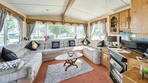 A spacious living area with a large sofa set, a dining table, and a kitchen area. - 3 Bed - Sleeps 8 - Sea View - Pets - Parking (Filey)