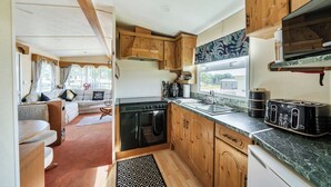 A compact kitchen with wooden cabinets, a stove, and a sink. - 3 Bed - Sleeps 8 - Sea View - Pets - Parking (Filey)