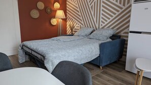 Une chambre à coucher avec un lit, une lampe de chevet, une horloge murale et un papier peint à motifs.