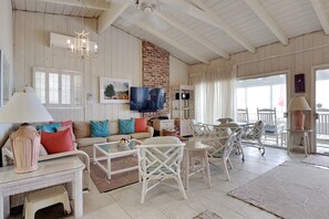 A cozy living room with a sofa, chairs, a TV, and a fireplace. - Trident Ocean Front & Pet Friendly (Pawleys Island)