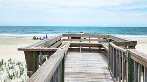 Ein Holzsteg führt zu einem Strand mit freiem Blick auf den Ozean.