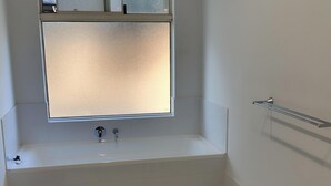 Een badkamer met een bad, een raam en een handdoekhouder.