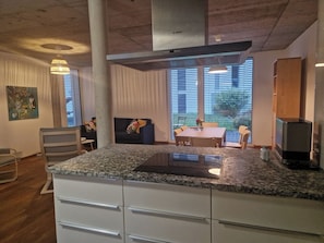 Una cocina moderna con encimera de granito, armarios blancos y extractor Bosch.