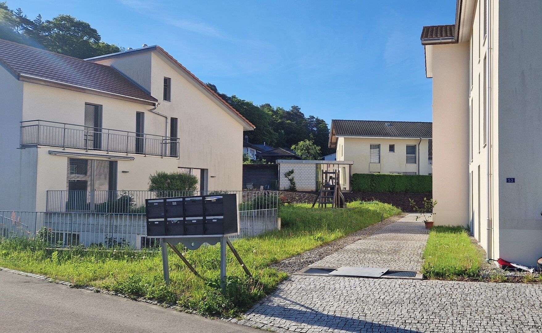 Zona residencial amb cases modernes, un camí de grava i una tanca metàl·lica.