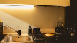 Una cocina con un lavamanos, un hervidor, una cafetera y un dispensador de jabón.