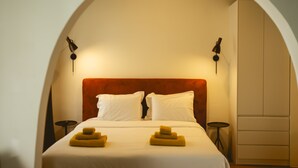 Una habitación de hotel con una cama, dos mesitas de noche y un armario.