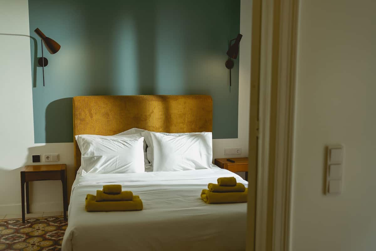 Habitació d'hotel amb un llit, una taula de nit, una làmpada i una làmpada de paret.