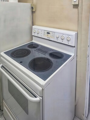 A white stove with four burners and a control panel. - Studio Efficiency Apartment (Port Saint Lucie)