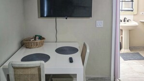 Ein Essbereich mit Tisch, Stühlen, einem Fernseher und einer wandmontierten Klimaanlage.