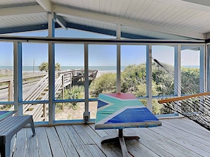 A covered outdoor area with a view of the beach, a hammock, and a table. - Dog Friendly- Oceanfront Litchfield Beach! The Flag House - Traumerei (Pawleys Island)