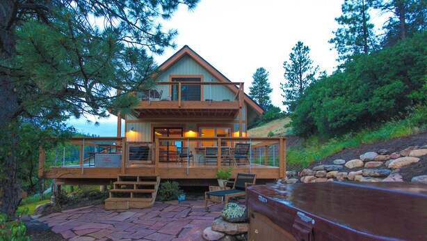 A two-story log cabin with a deck, stone patio, and hot tub. - Downtown Oasis with View, Hot Tub & Fire Pits (Pagosa Springs)