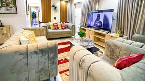 Una sala de estar moderna con un juego de sofá, televisor e iluminación decorativa en el techo.