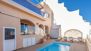 En modern byggnad med en swimmingpool, utomhusplats och en stenmur.