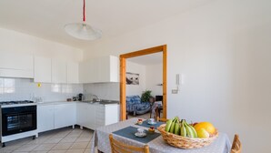 Uma cozinha com armários brancos, fogão e uma área de jantar com mesa posta para dois.