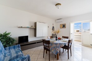 Ein Essbereich mit einem Tisch für vier Personen, einer Couch, einem Fernseher und einem Schrank.