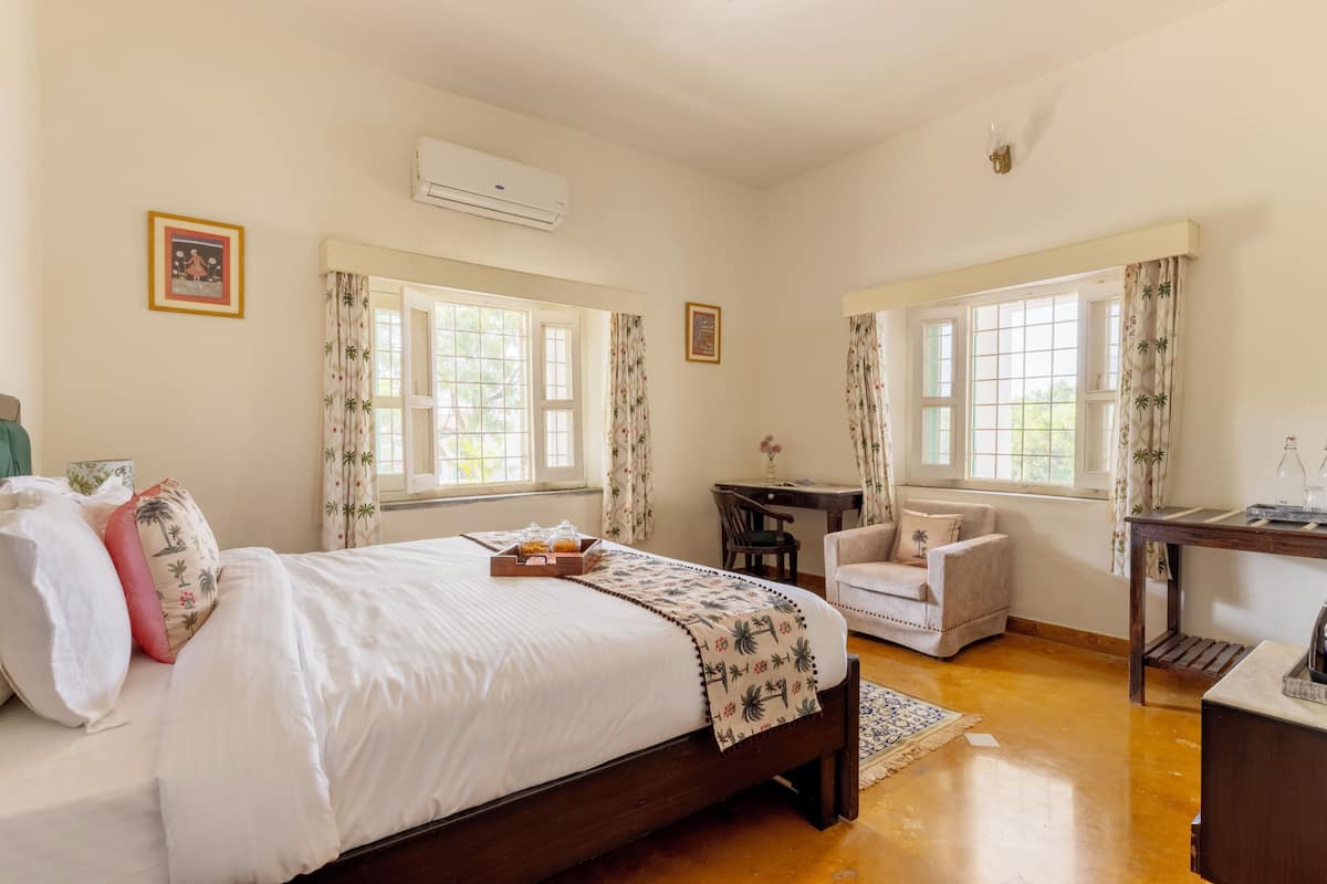 A bedroom with a bed, a desk, a chair, and a window.