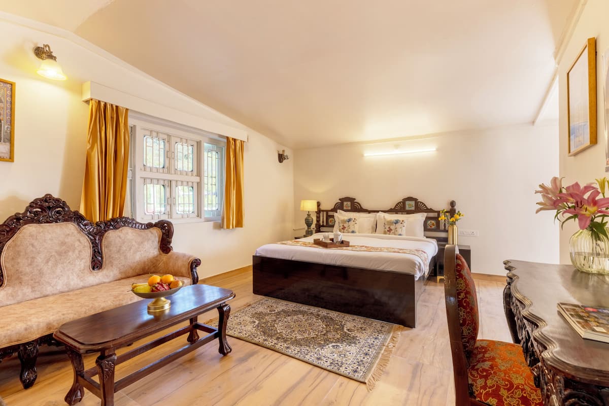 A room with a sofa, a bed, a table with fruit, and a patterned rug.