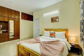 Un dormitorio con una cama de madera, una mesita de noche con lámpara, un armario y un cuadro en la pared.